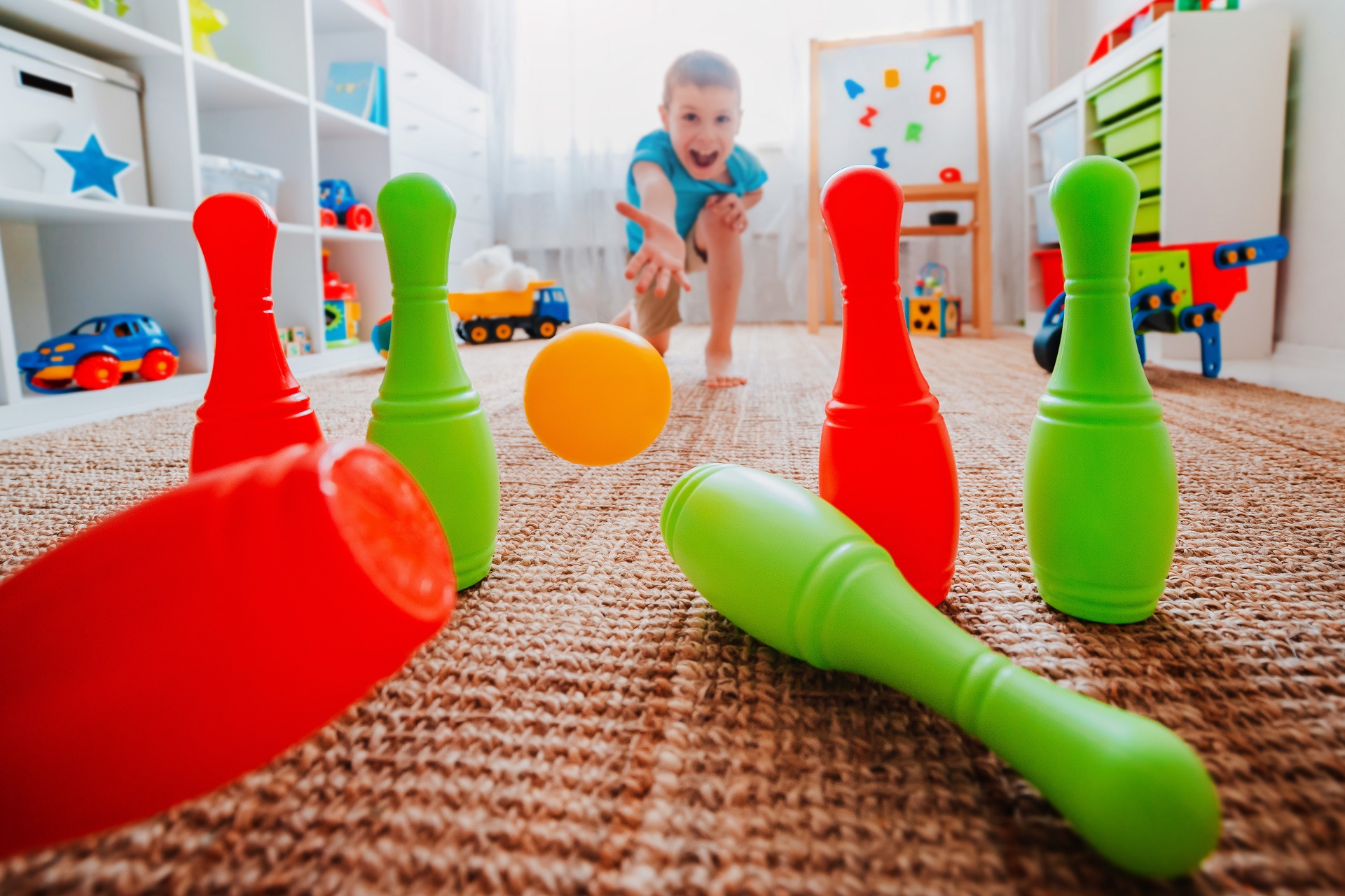 menino brincando de boliche plástico no quarto