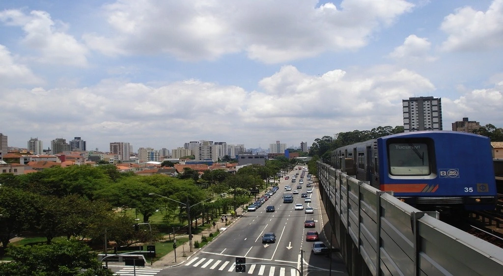 Avenida, ao lado o trem da CPTM passando em trilho elevado, representando a mobilidade urbana no bairro Campo Belo em São Paulo